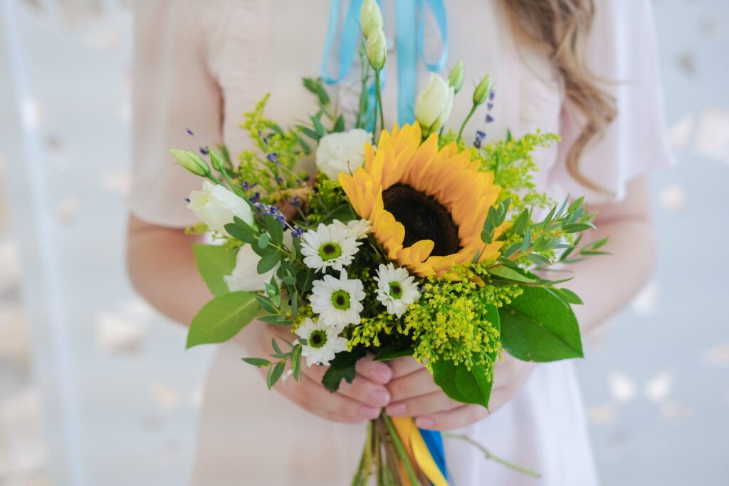 bunch of fresh elegant flowers in hands of crop unrecognizable bride